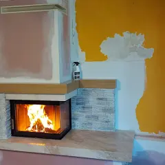 Nowy, nowoczesny kominek w salonie rozgrzewa wnętrze. Płomienie tańczą w palenisku, tworząc przytulną atmosferę.