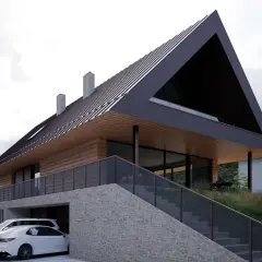 Nowoczesny dom na wzniesieniu z kamienną podstawą, drewnianymi elementami i dachem o ostrym kącie. Dwa białe samochody zaparkowane pod zadaszeniem.