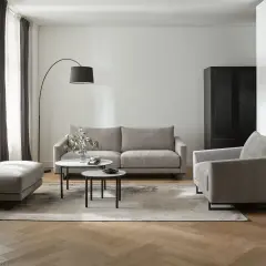 Nowoczesny salon z dwiema sofami, fotelem i pufą. W centrum dwie niskie stoliki kawowe.
