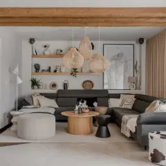 Przytulny salon w stylu boho z szarą sofą, plecionymi lampami i drewnianymi belkami.