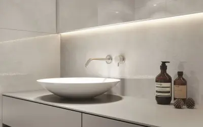 Nowoczesny blat do łazienki z umywalką nablatową i baterią ścienną. Minimalistyczny design, szare płytki i dyskretne oświetlenie.