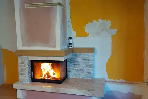 Nowy, nowoczesny kominek w salonie rozgrzewa wnętrze. Płomienie tańczą w palenisku, tworząc przytulną atmosferę.