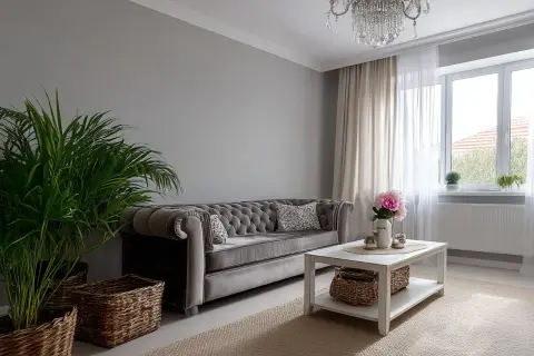 Elegancka sofa chesterfield i kryształowy żyrandol tworzą styl boho glamour wnętrza. Wazon z kwiatami i wiklinowe kosze dodają przytulności.