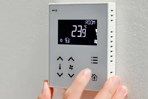 Dłoń dostosowuje **ekonomiczne ustawienie pompy ciepła** na termostacie. Wyświetlacz pokazuje 23.9°C.