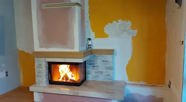 Nowy, nowoczesny kominek w salonie rozgrzewa wnętrze. Płomienie tańczą w palenisku, tworząc przytulną atmosferę.