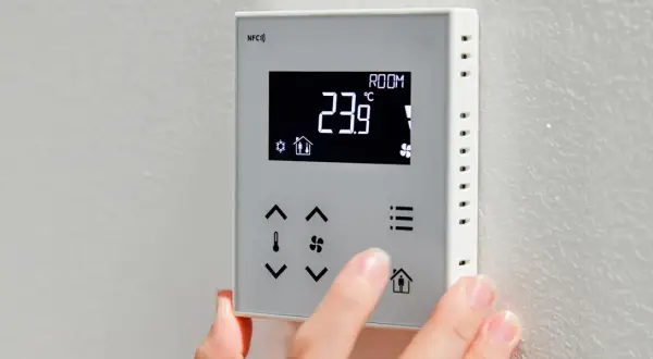 Dłoń dostosowuje **ekonomiczne ustawienie pompy ciepła** na termostacie. Wyświetlacz pokazuje 23.9°C.