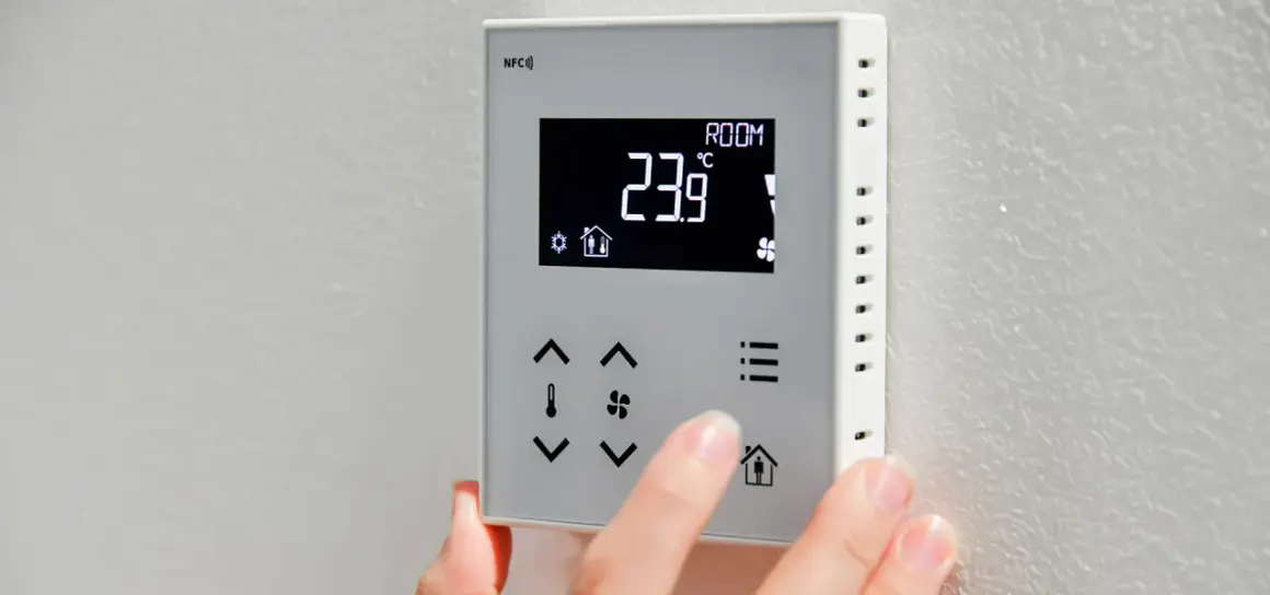 Dłoń dostosowuje **ekonomiczne ustawienie pompy ciepła** na termostacie. Wyświetlacz pokazuje 23.9°C.