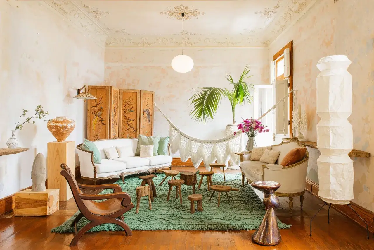 Relaks w stylu boho wnętrza: białe sofy, pleciony hamak, drewniane stołki i egzotyczne rośliny tworzą przytulną atmosferę.