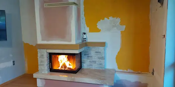 Nowy, nowoczesny kominek w salonie rozgrzewa wnętrze. Płomienie tańczą w palenisku, tworząc przytulną atmosferę.